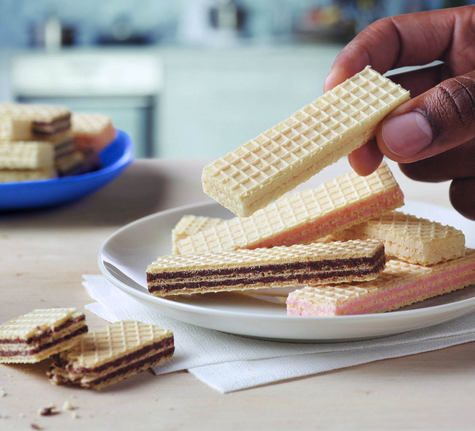 Close-up of someone holding a wafer with other flavours of wafers on a plate