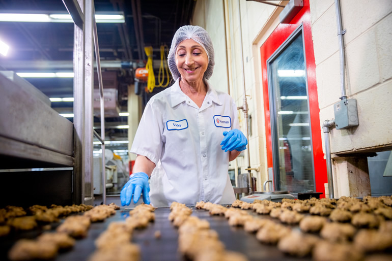 Voortman baker checking a large batch of cookies on a conveyor sheet coming out of the oven